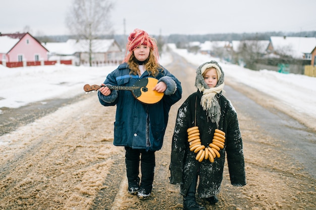 Enfants drôles en plein air. Jeunes au village. Vêtements traditionnels de style russe. Deux petites filles bizarre inhabituelle étrange portrait. Enfants portant des vêtements adultes surdimensionnés.