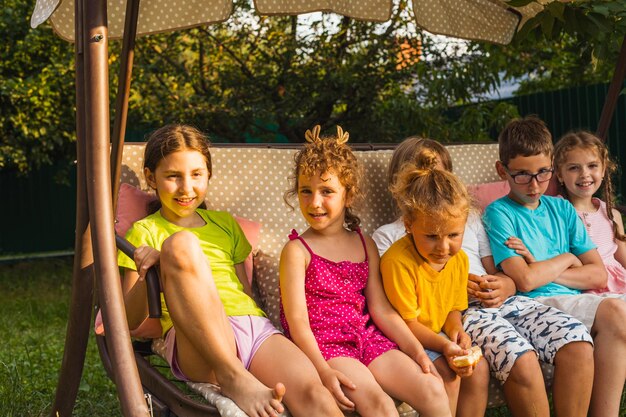 Enfants drôles reposant sur une grande balançoire de jardin