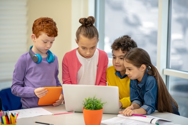 Les enfants de l'école debout ensemble devant l'ordinateur portable