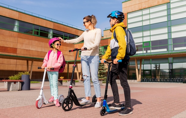 enfants d'école heureux avec leur mère sur des scooters