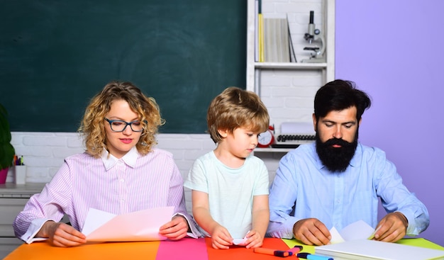 Enfants de l'école. Partenariat école-famille. Journée familiale. Jeune couple aidant son fils à faire ses devoirs. Début des cours. L'éducation des enfants non scolarisés. Les parents se sentent fiers des progrès de leur fils.