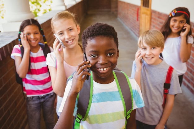 Photo enfants de l'école utilisant des téléphones cellulaires dans le couloir de l'école