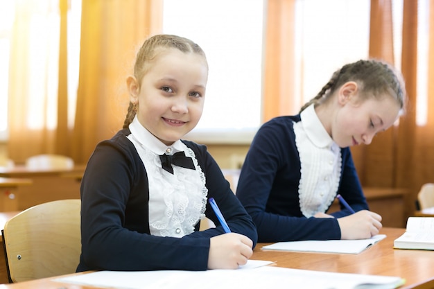 Les enfants écrivent assis au bureau de l'école.