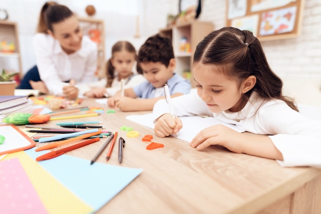 Les enfants écrivent dans des cahiers avec un stylo.