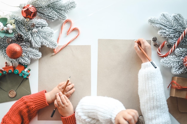 Les enfants écrivent une lettre au Père Noël sur des feuilles d'artisanat, un espace de vue de dessus pour votre texte