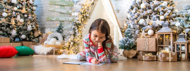 Les enfants écrivent une lettre au Père Noël sous l'arbre Mise au point sélective