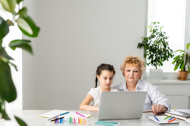 Enfants et éducation, enseignant ou grand-mère enseignant avec un ordinateur portable par internet à une fille.