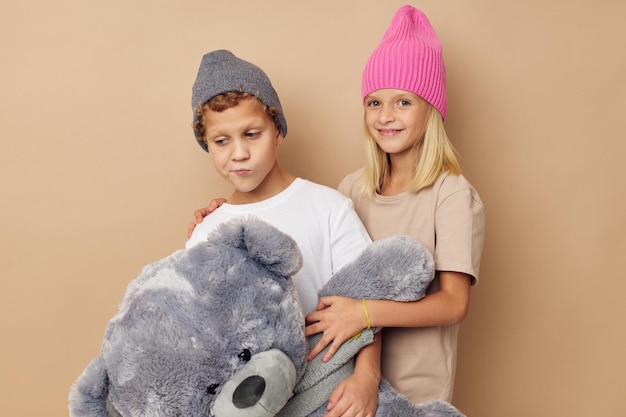 Enfants élégants mignons dans des chapeaux avec une amitié d'ours en peluche