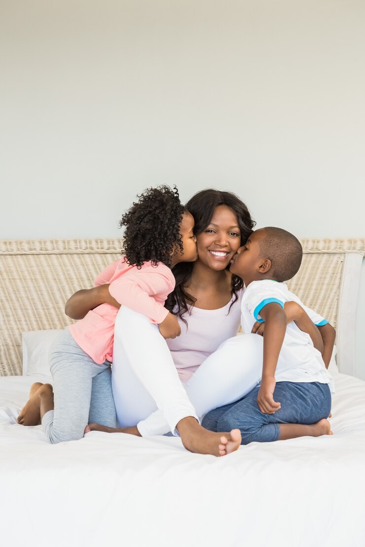 Enfants embrassant la mère sur le lit