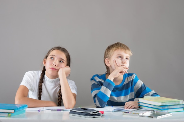 Enfants ennuyés assis près de la table et regardant au loin