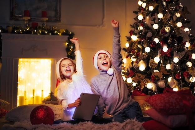 Enfants excités près de l'arbre de Noël