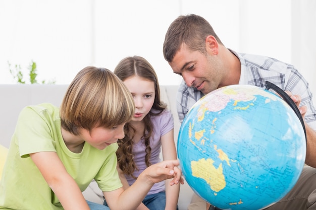 Enfants explorant le globe en étant assis avec le père