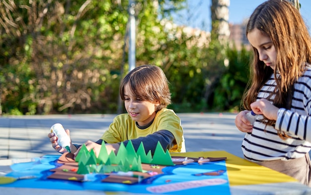 Enfants faisant de l'artisanat à une table dans le parc