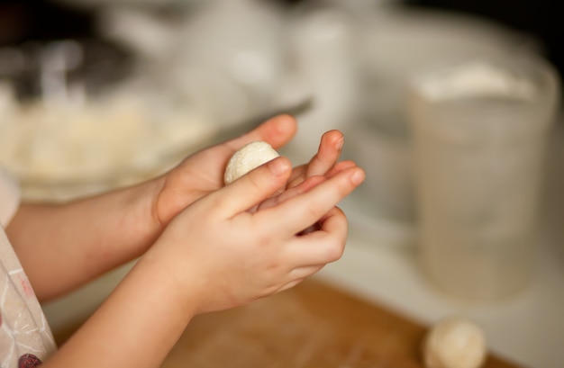 Enfants faisant des boules de fromage cottage syrniki russe dans la cuisine à domicile.