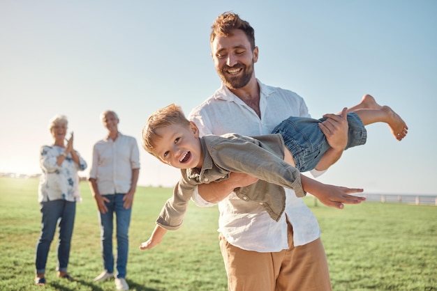 Photo enfants de la famille et jouant avec un homme et son fils s'amusant en plein air dans un champ dans la nature avec des grands-parents enfants d'été et amour avec un père et un garçon enjoués à l'extérieur pour créer des liens en vacances