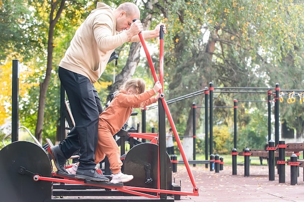 Les enfants de la famille se promènent sur le terrain de sport de la ville et font des exercices avec leurs parents