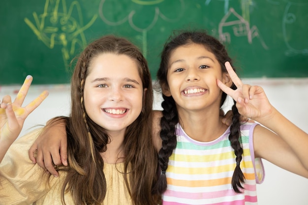 Enfants fille mix race sourire heureux en classe d'école avec fond de tableaux