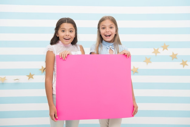 Les enfants filles tiennent un espace de copie d'affiche publicitaire Les enfants tiennent une bannière publicitaire Des enfants heureux avec du papier vierge pour la publicité Concept de publicité Votre publicité entre de bonnes mains