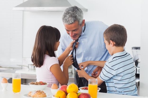 Enfants fixant leurs pères cravate dans la cuisine