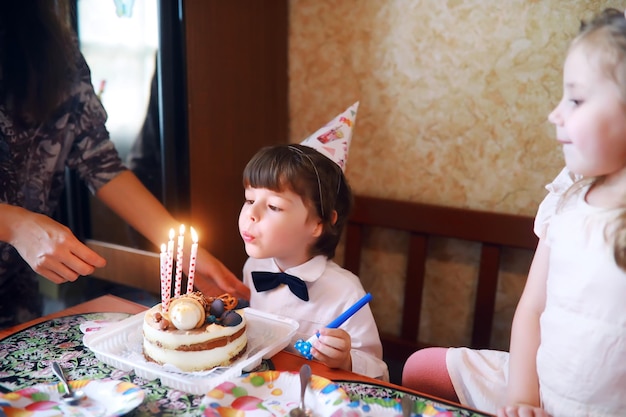 Les enfants font la fête en casquettes pour célébrer leur anniversaire avec des gâteaux et des ballons à la maison.