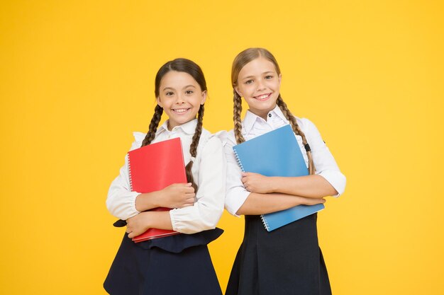 Les enfants de la fraternité apprennent la grammaire de retour à l'école les petites filles en uniforme scolaire lisant l'histoire de la littérature pour enfants dictionnaire cahier Obtenir des informations camarades de classe joyeux avec cahier