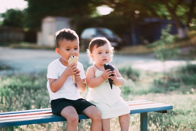 enfants, frère et soeur sur le banc, manger de la glace est très amusant et mignon