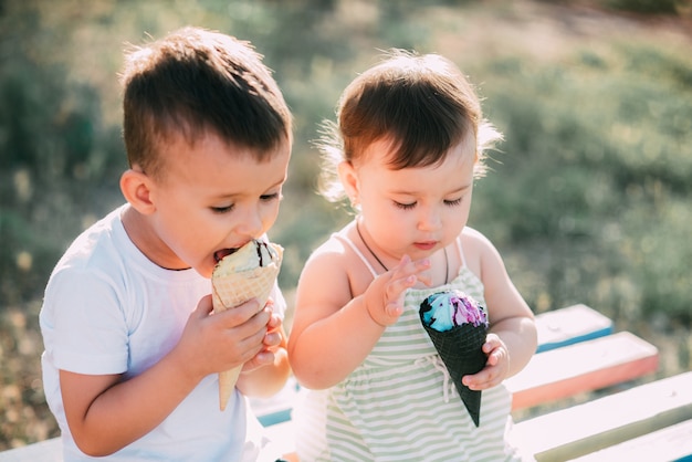 enfants, frère et soeur sur le banc, manger de la glace est très amusant et mignon