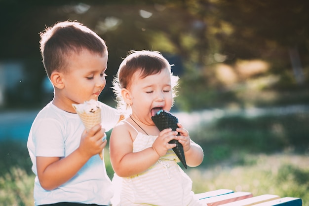enfants, frère et soeur sur le banc, manger de la glace est très amusant et mignon