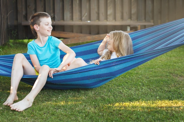 Enfants frère et soeur se reposant dans le jardin sur un hamac