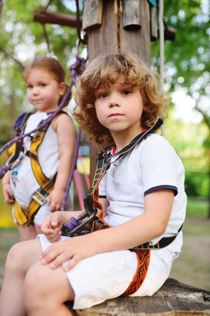 Enfants - un garçon et une fille dans le parc à corde franchissent des obstacles.