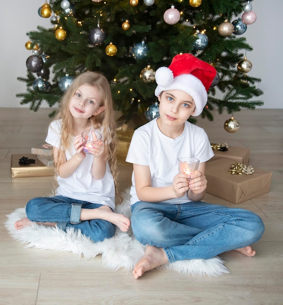 Les enfants un garçon et une fille jouent près de l'arbre de Noël