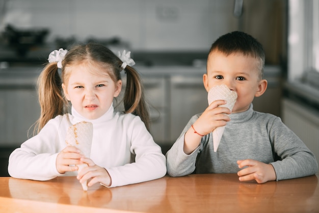 enfants garçon et fille mangeant un cornet de crème glacée dans la cuisine est très amusant très doux