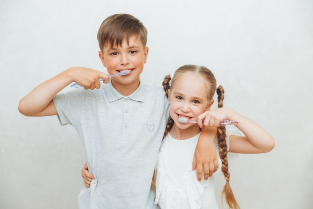 Enfants un garçon et une fille se brossent les dents et rient isolés sur fond blanc dentisterie pédiatrique hygiène et nettoyage des dents