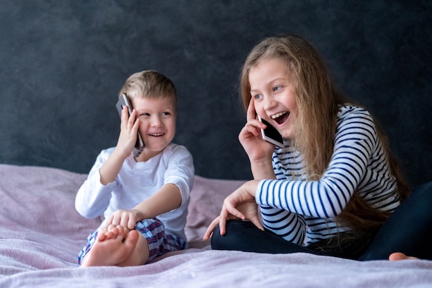 Les enfants et les garçons caucasien exsited parlent sur les téléphones mobiles à la maison.