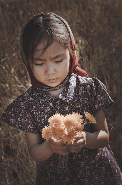 enfants et guerre, une petite villageoise asiatique dans un champ de fleurs
