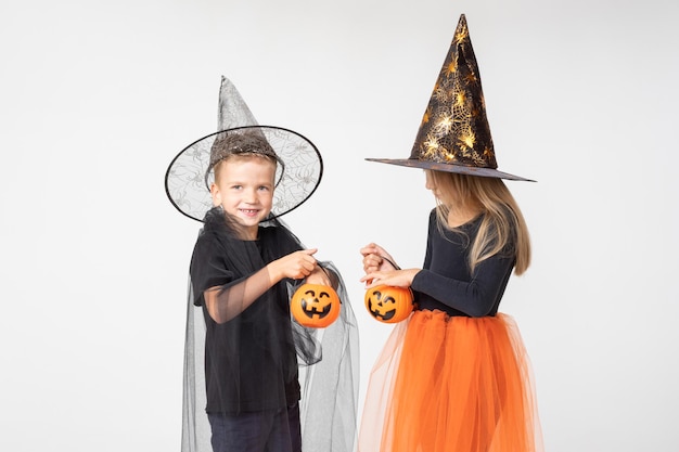 Enfants Halloween Une belle fille mignonne dans un costume de sorcière et un garçon dans un costume de sorcier sortent des bonbons d'un panier