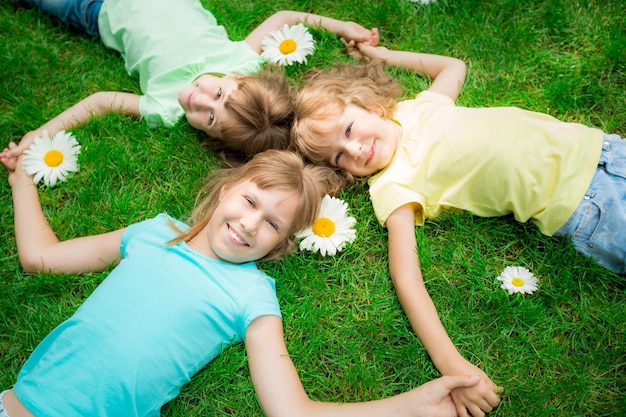 Enfants heureux allongés sur l'herbe Enfants drôles jouant dans le parc Belles fleurs de printemps