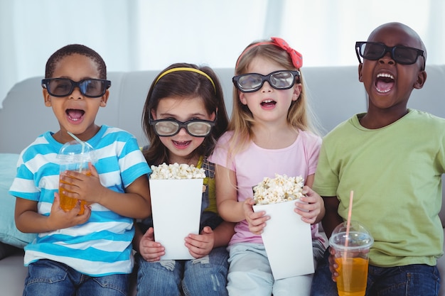 Enfants heureux bénéficiant de pop-corn et des boissons en position assise