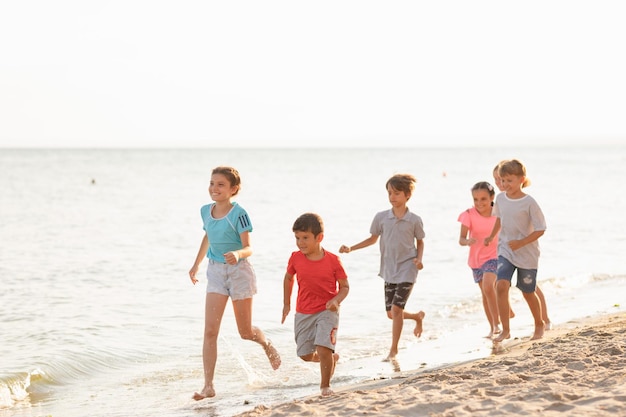 Photo enfants heureux courant sur la plage enfants joyeux s'amusant pendant les vacances d'été