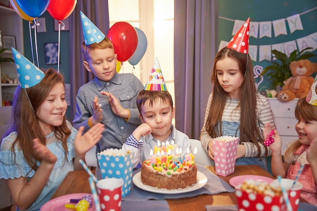 Enfants heureux dans des casquettes de fête célébrant un anniversaire