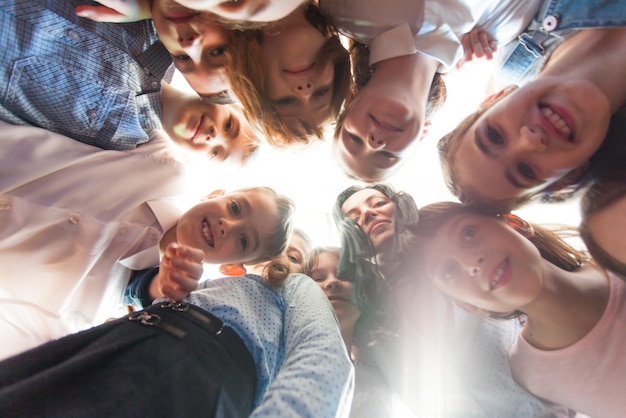 Enfants heureux avec une enseignante dans un cercle regardant vers le bas