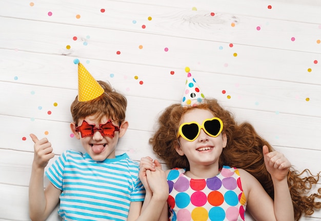 Enfants heureux sur la fête de carnaval, allongé sur un plancher en bois. Enfance heureuse, concept de vacances.