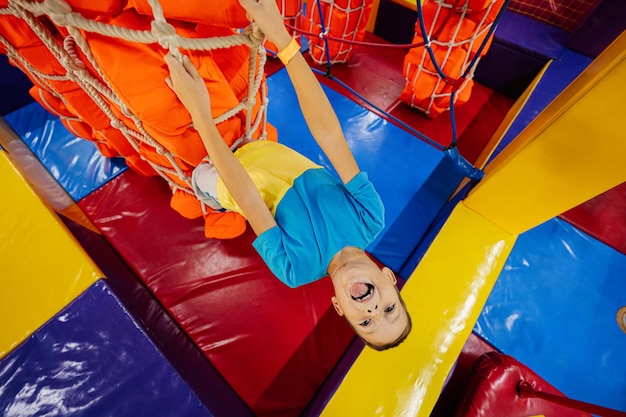 Enfants heureux jouant au centre de jeux intérieur, le garçon grimpe les cordes