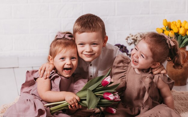 Des enfants heureux jouent et rient dans une pièce fleurie. Garçon et deux filles