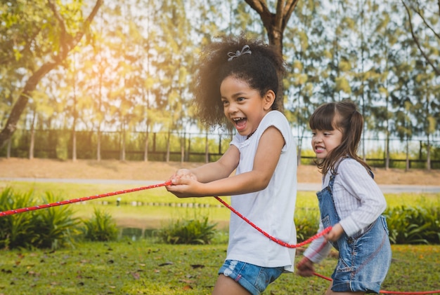 Photo enfants heureux, jouer à la corde tir à la corde dans le parc