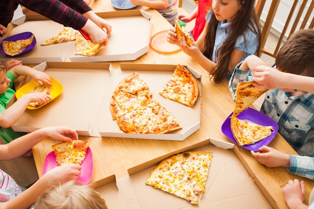 Enfants heureux mangeant de la pizza profitant d'une fête d'anniversaire au café. Collation enfants