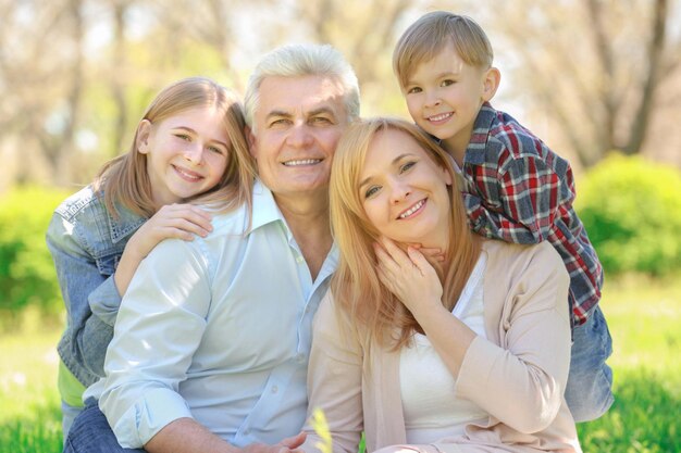 Enfants heureux mignons avec leurs grands-parents dans le parc du printemps par une journée ensoleillée