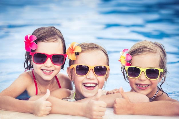 Enfants heureux montrant les pouces vers le haut dans la piscine Enfants amusants jouant à l'extérieur Concept de vacances d'été