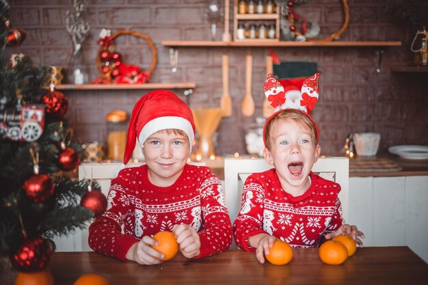 Enfants heureux avec des oranges dans la cuisine sombre à la maison la veille de Noël se préparant pour les vacances joyeux Noël et une joyeuse nouvelle année