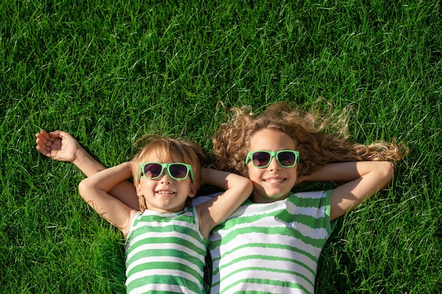 Des enfants heureux portant sur l'herbe verte. Enfants drôles en plein air dans le jardin de printemps.